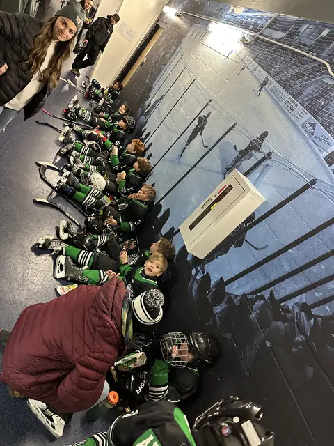 Players seated down the hallway, geared up and waiting to take the ice
